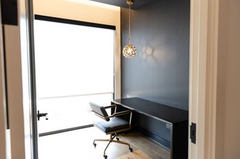 A black desk with a chair and a hanging light fixture.